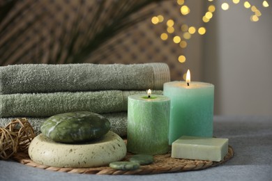 Photo of Spa composition. Burning candles, stones, soap and towels on grey table