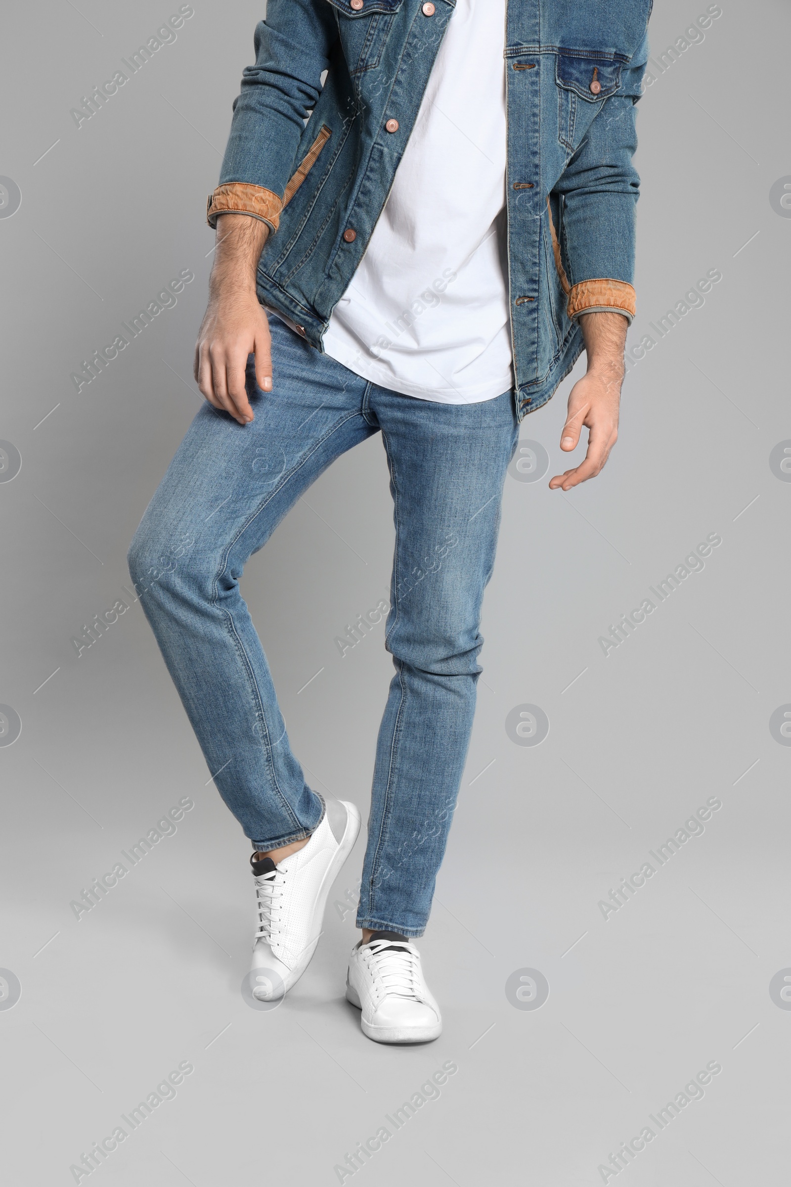 Photo of Young man in stylish jeans on grey background, closeup