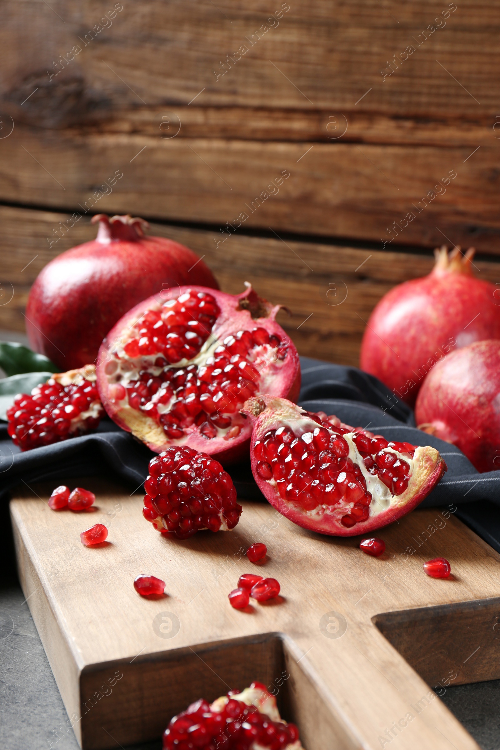 Photo of Ripe pomegranates on board against wooden background