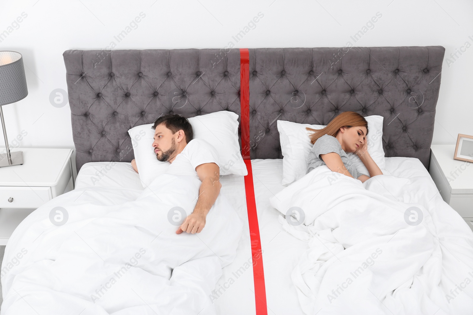 Photo of Upset couple with relationship problems lying separately in bed at home