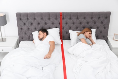 Photo of Upset couple with relationship problems lying separately in bed at home