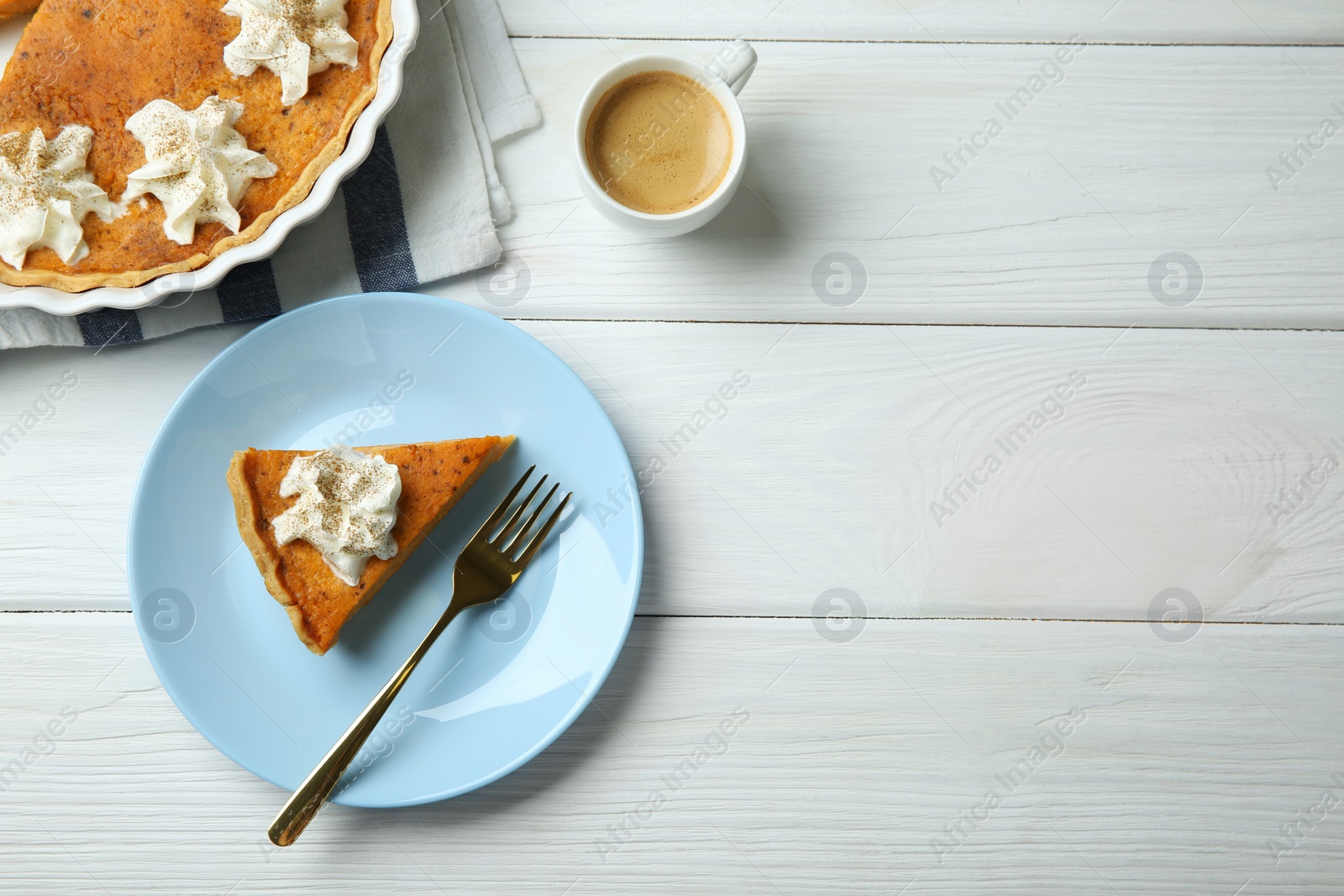 Photo of Delicious pumpkin pie with whipped cream, fork and cup of coffee on white wooden table, flat lay. Space for text