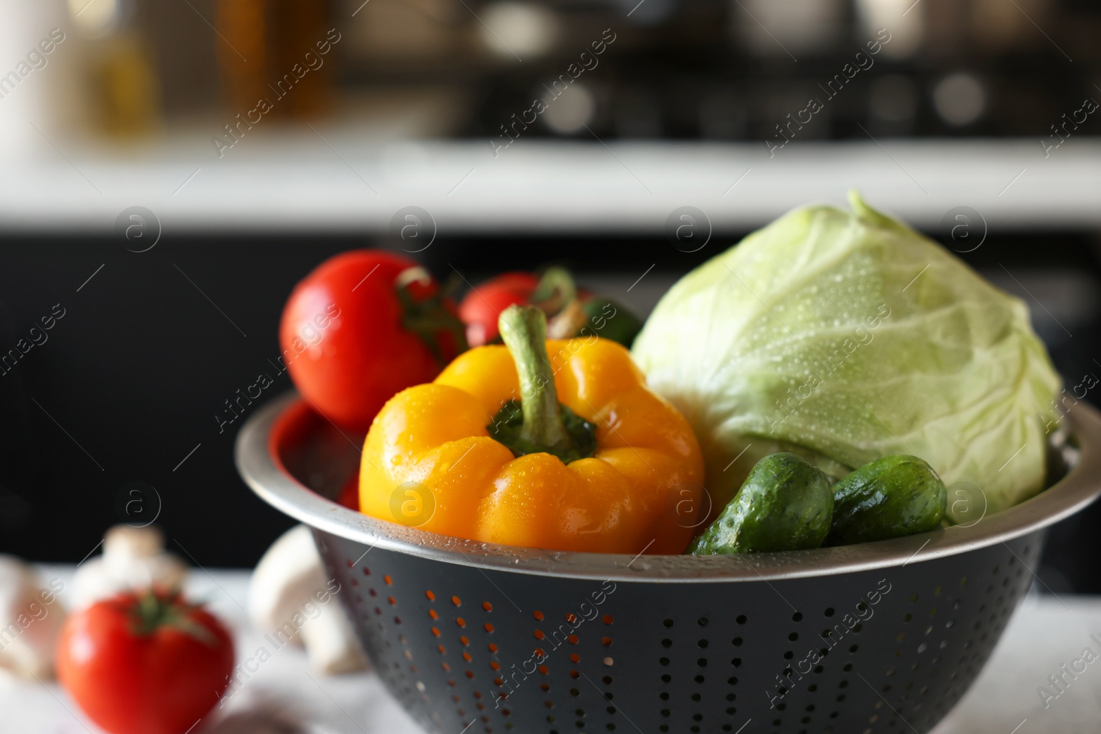 Photo of Metal colander with different wet vegetables on table, closeup