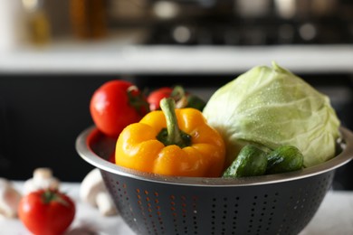 Metal colander with different wet vegetables on table, closeup