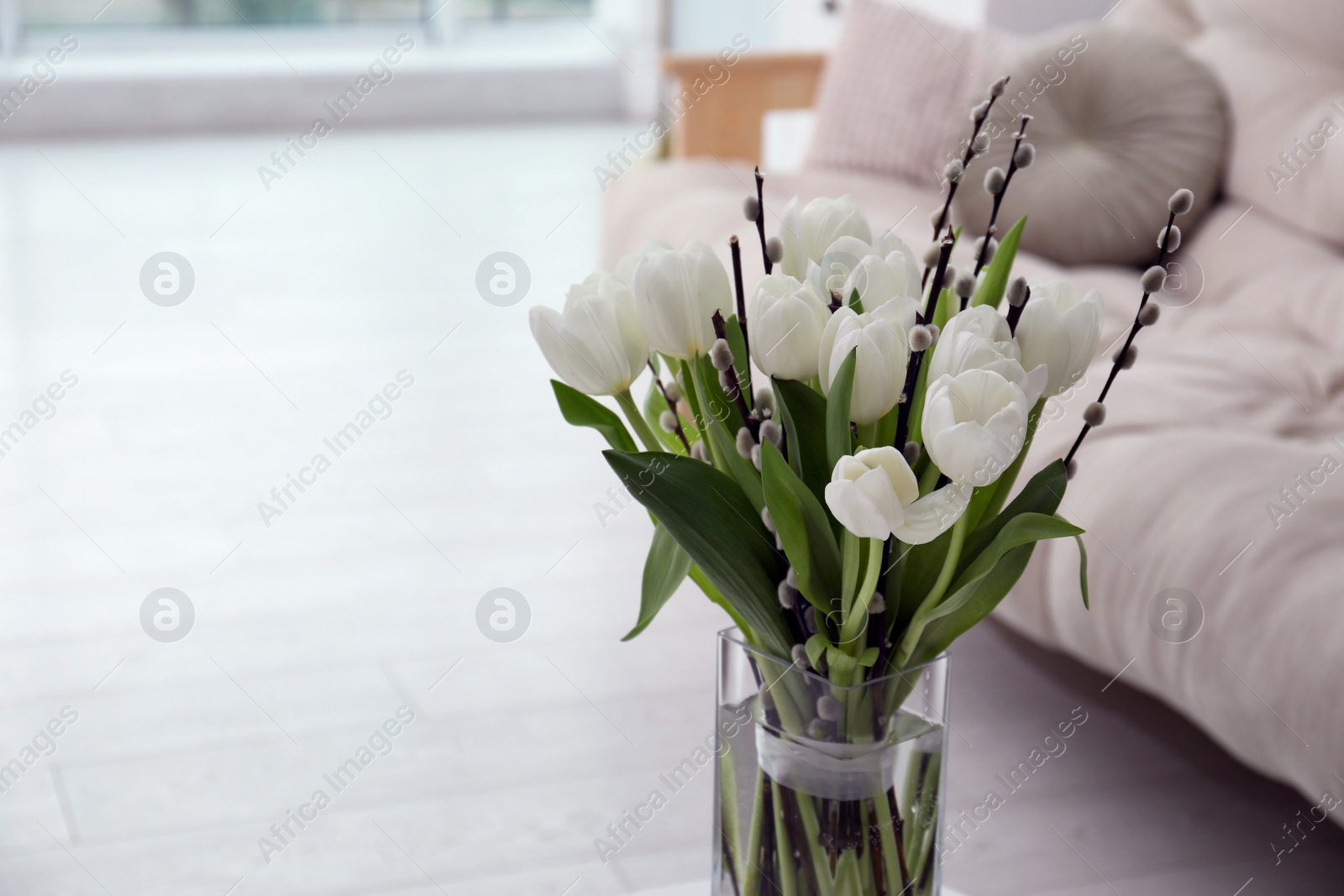 Photo of Beautiful bouquet of willow branches and tulips in vase indoors, space for text