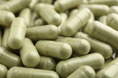 Light green vitamin capsules as background, closeup