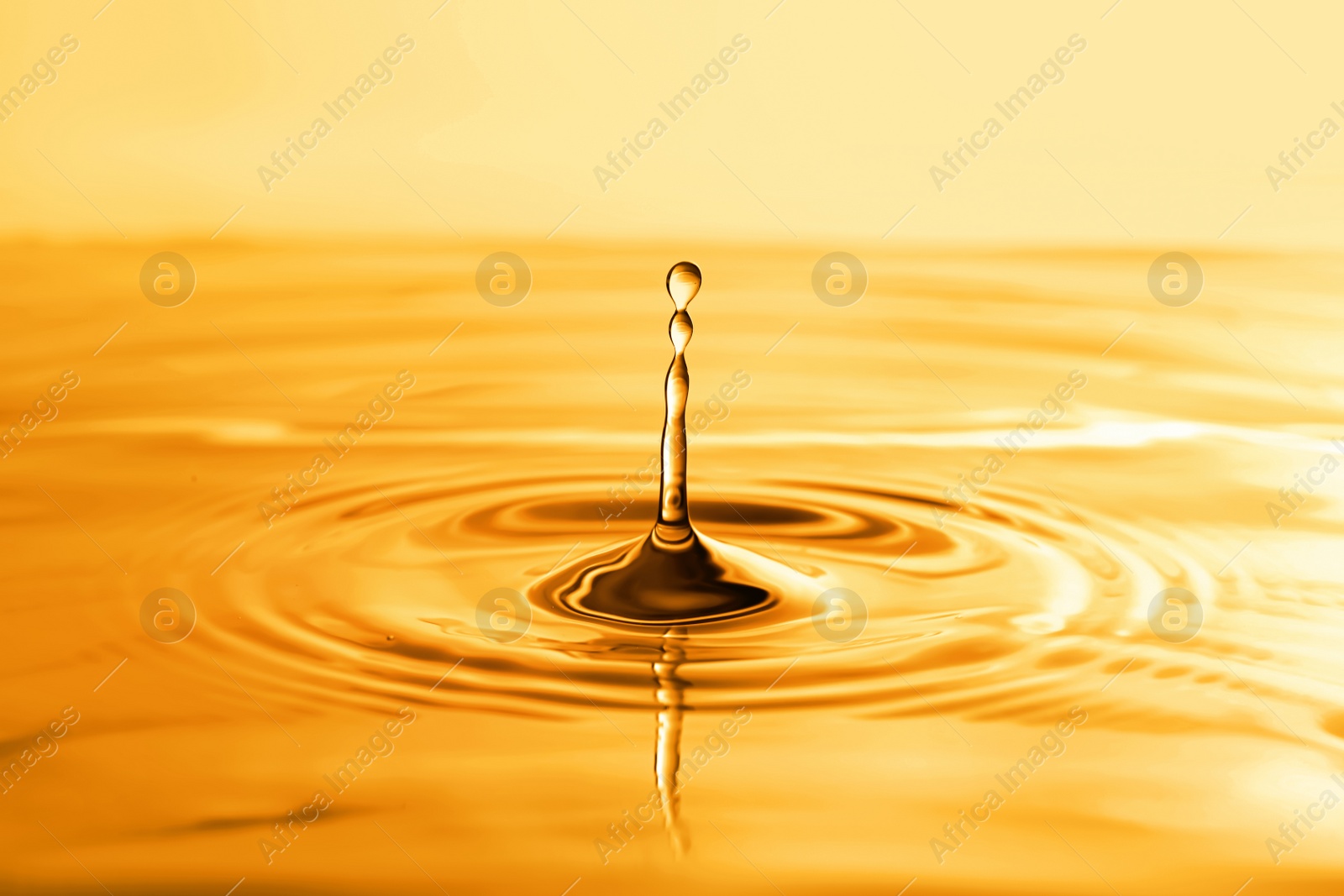 Image of Splash of golden oily liquid with drops as background, closeup