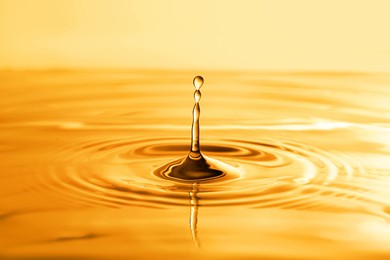 Splash of golden oily liquid with drops as background, closeup