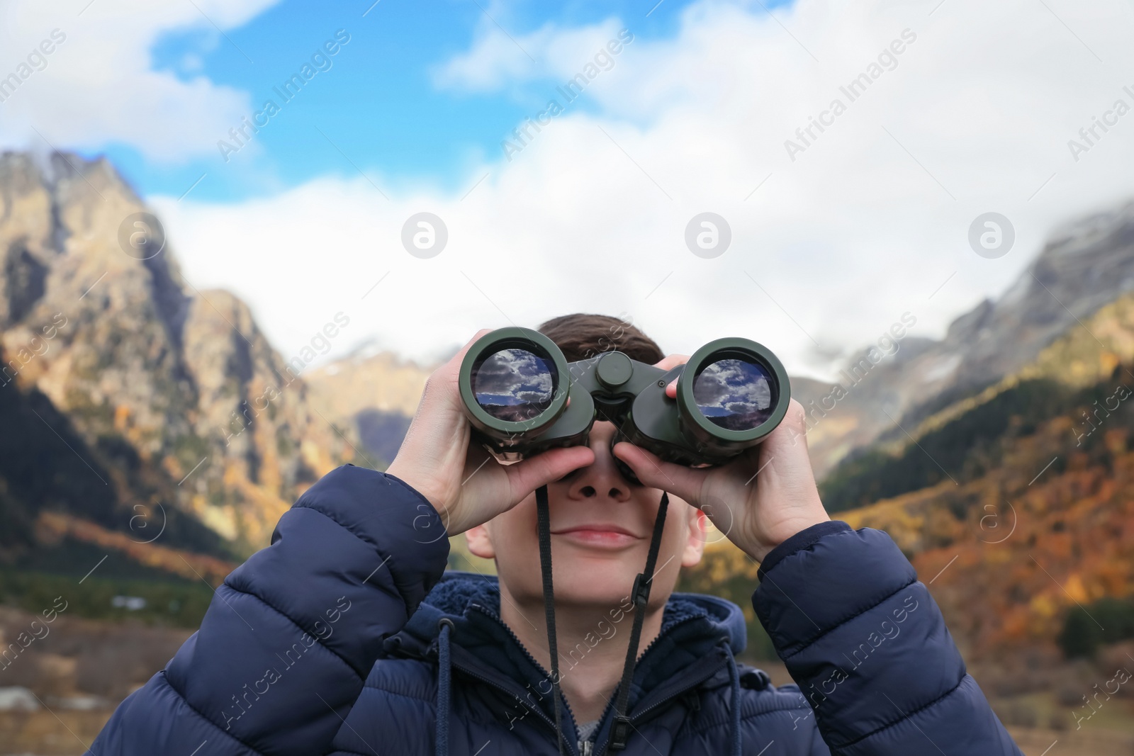 Photo of Boy looking through binoculars in beautiful mountains, closeup