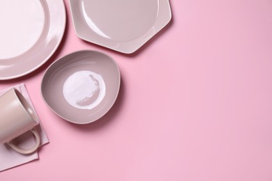 Set of ceramic dishware on light pink background, flat lay. Space for text