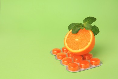 Photo of Fresh orange, mint leaves and blister with cough drops on light green background. Space for text