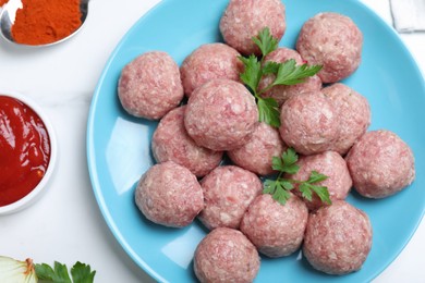 Many fresh raw meatballs on white table, flat lay