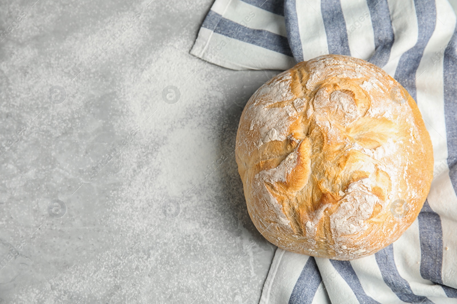 Photo of Loaf of fresh bread on grey marble background, top view. Space for text