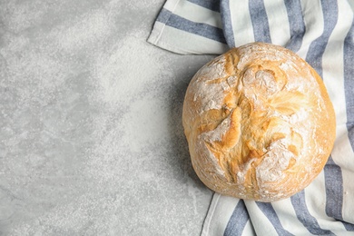 Loaf of fresh bread on grey marble background, top view. Space for text