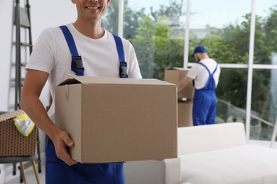 Moving service employees with cardboard boxes in room, closeup
