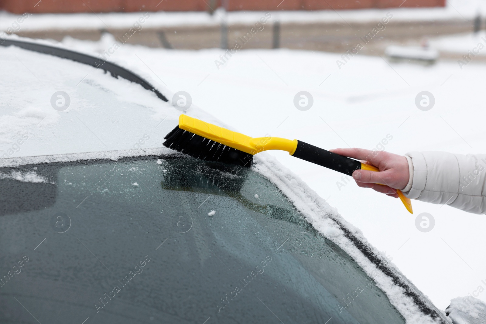 Photo of Man cleaning snow from car windshield outdoors, closeup