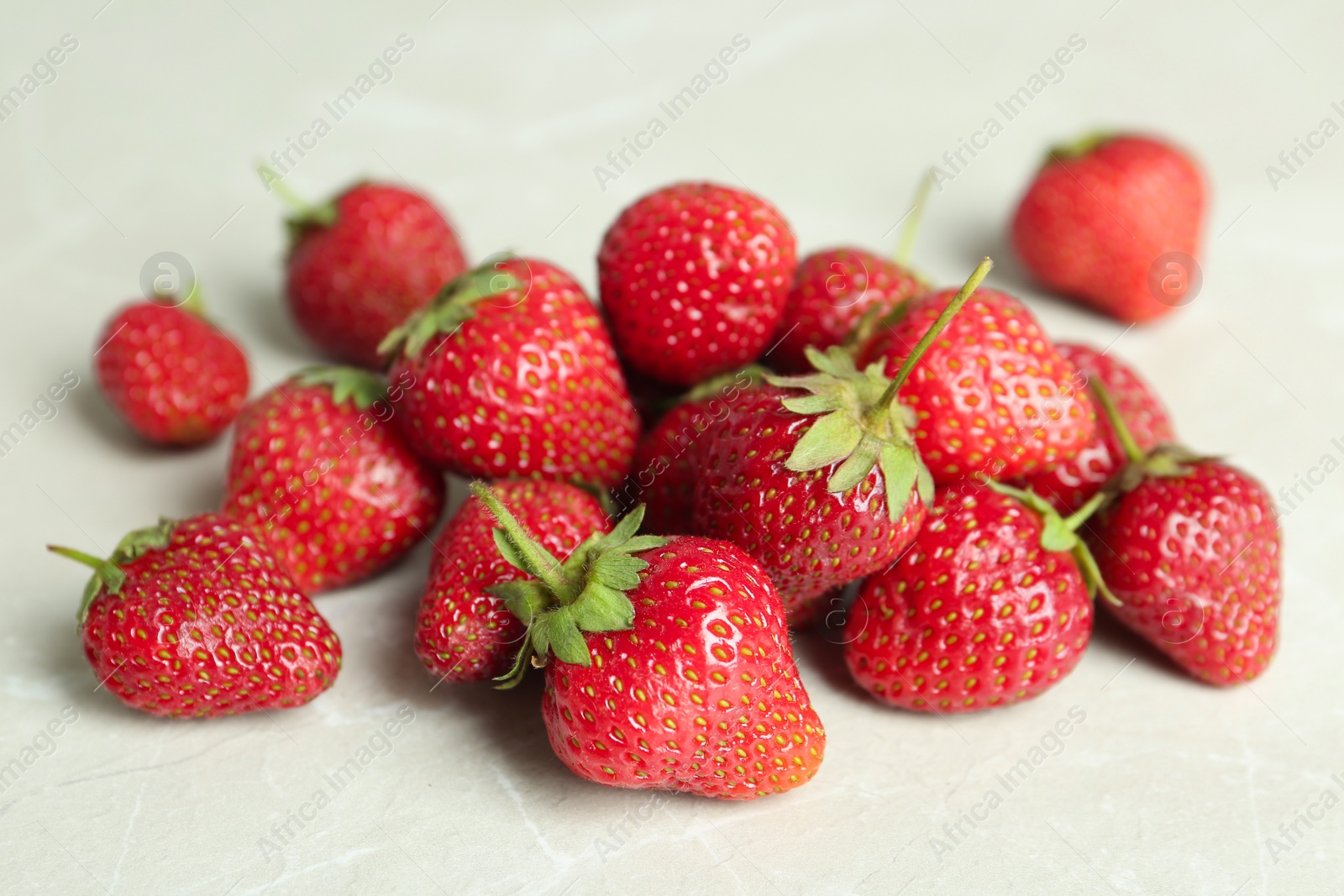 Photo of Delicious ripe strawberries on light grey table, closeup