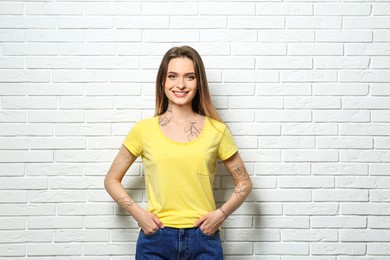 Image of Attractive woman with beautiful tattoo sketches near white brick wall