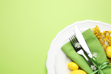 Photo of Festive Easter table setting with floral decor on green background, top view. Space for text