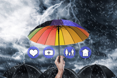 Image of Insurance agent covering illustrations with rainbow umbrella during storm