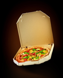 Hot tasty vegetable pizza in cardboard box on dark background. Image for menu or poster