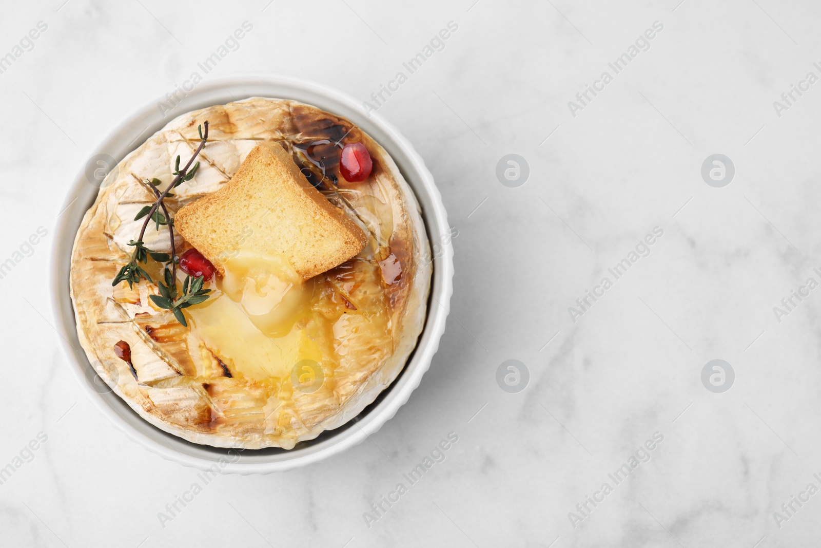 Photo of Tasty baked camembert with crouton and thyme on white marble table, top view. Space for text