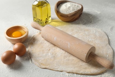 Raw dough, rolling pin and ingredients on table