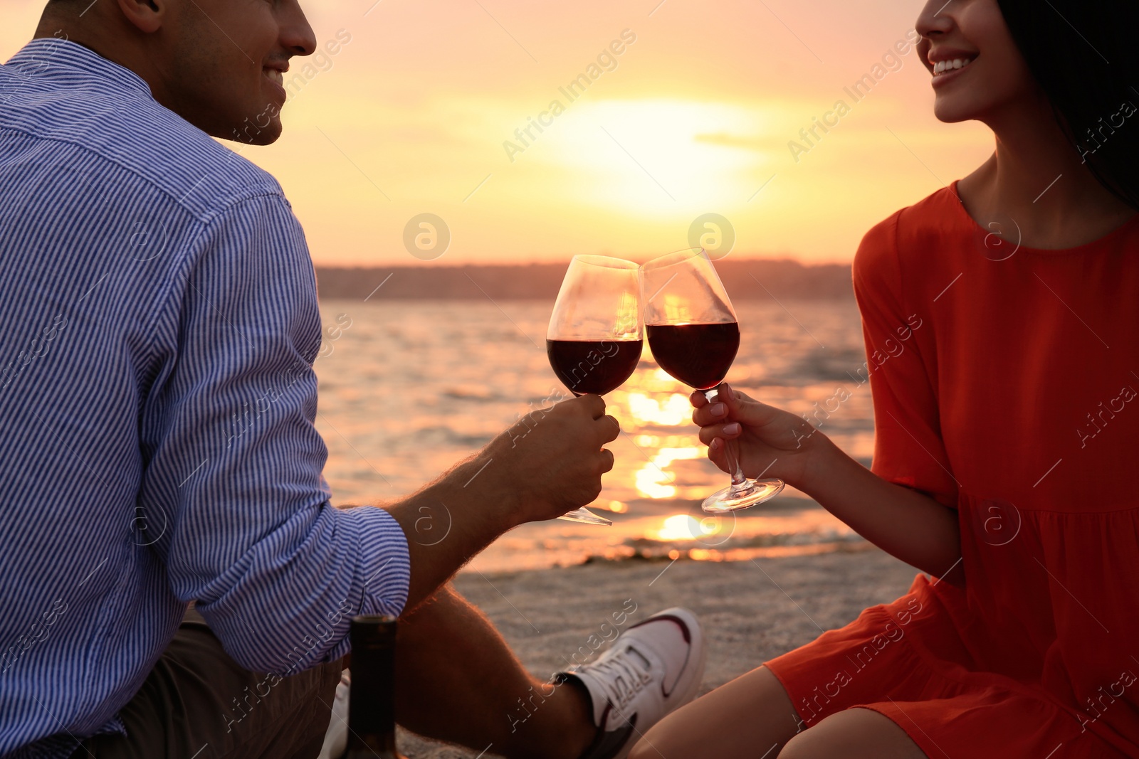 Photo of Lovely couple having picnic near river at sunset, closeup