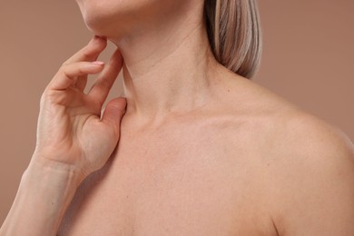 Photo of Woman touching her neck on beige background, closeup