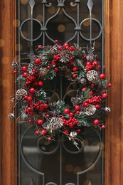 Photo of Beautiful Christmas wreath hanging on wooden door