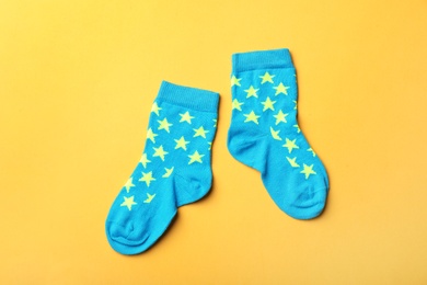 Pair of cute child socks on color background, top view