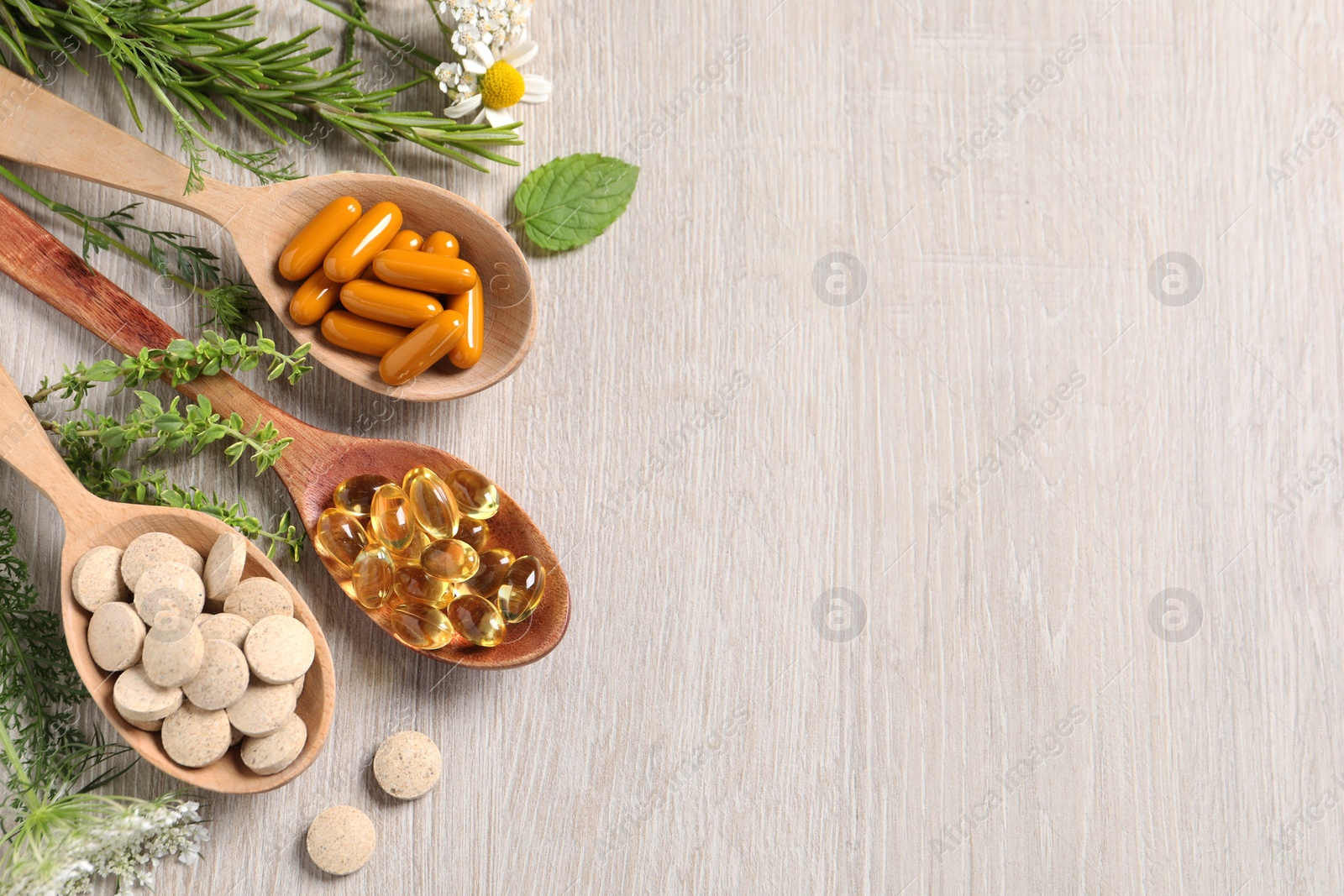 Photo of Different pills, herbs and flowers on wooden table, flat lay with space for text. Dietary supplements