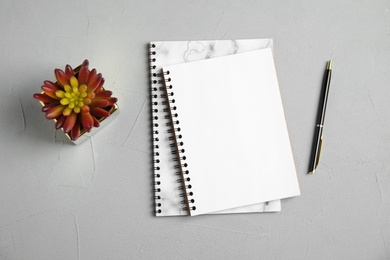 Photo of Flat lay composition with notebooks and plant on grey background