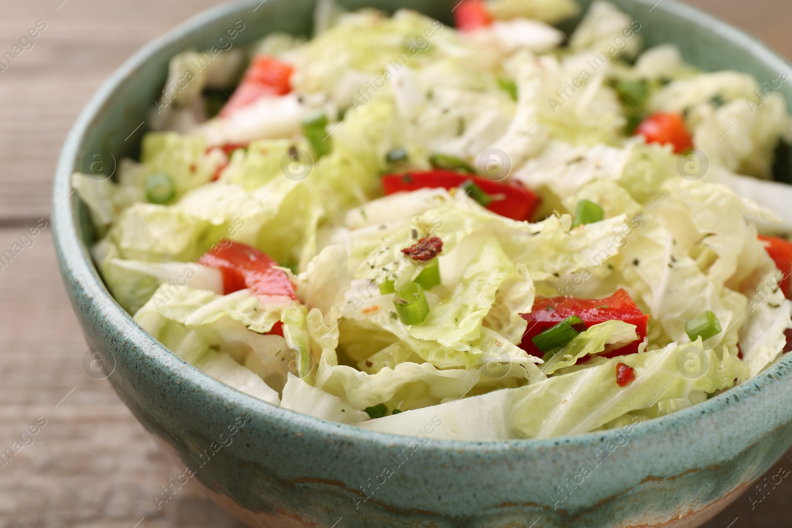 Photo of Tasty salad with Chinese cabbage, bell pepper and green onion in bowl on wooden table, closeup