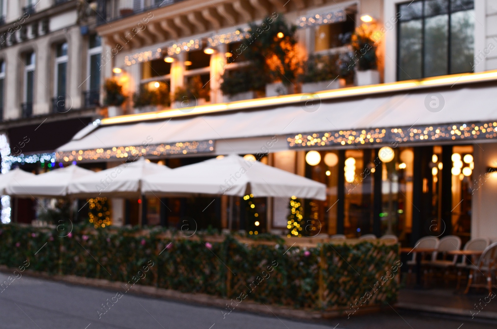 Photo of Blurred view of outdoor cafe terrace with beautiful lights in city