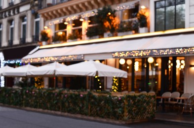 Blurred view of outdoor cafe terrace with beautiful lights in city