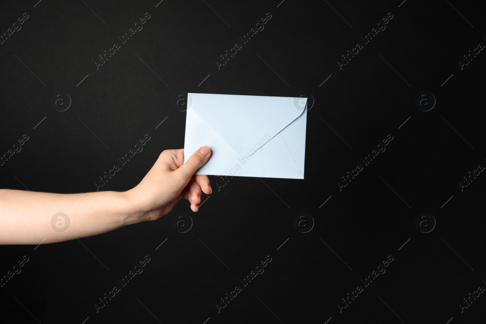 Photo of Woman holding white paper envelope on black background, closeup