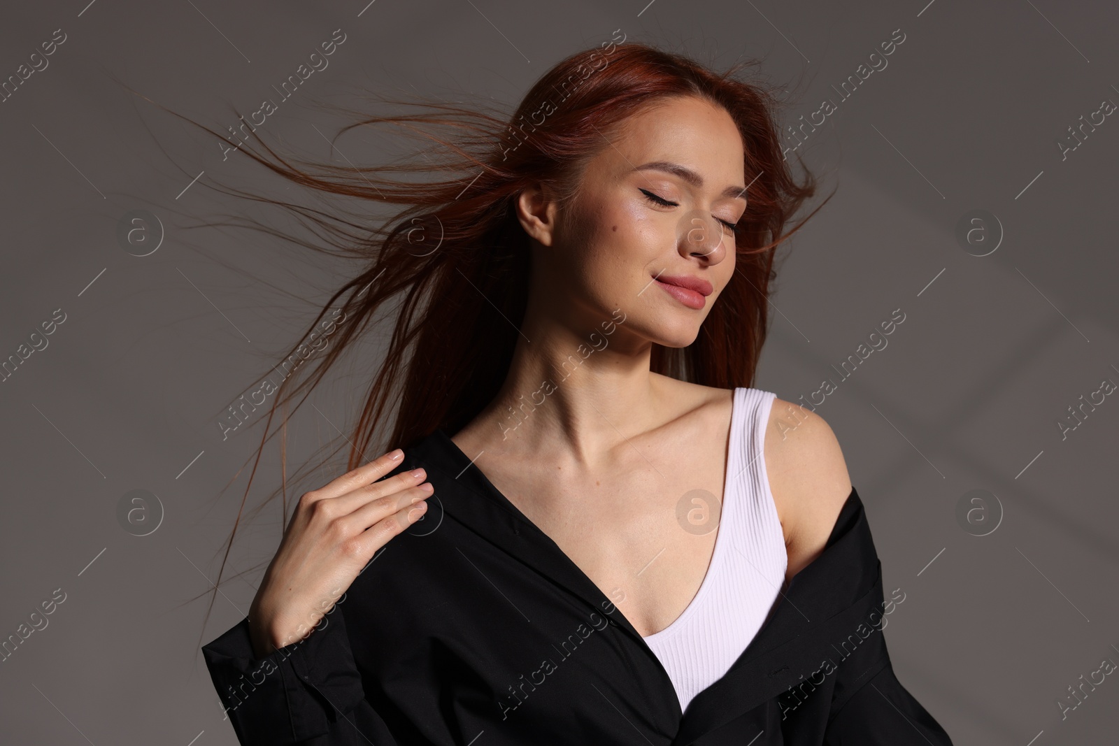 Photo of Beautiful young woman in black shirt on gray background