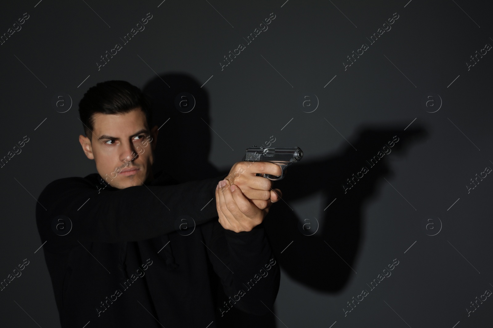 Photo of Professional killer with gun on black background