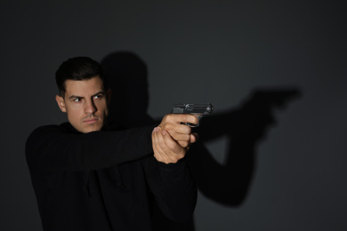 Professional killer with gun on black background