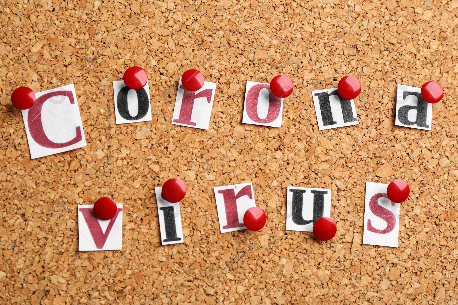 Photo of Words CORONA VIRUS pinned to corkboard, closeup