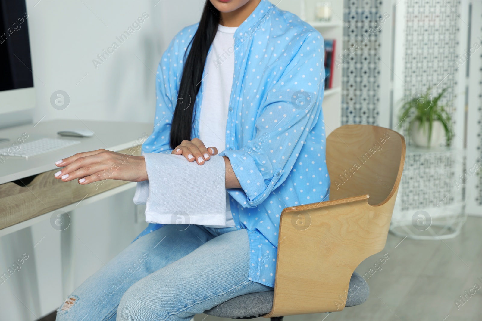 Photo of Woman using heating pad at home, closeup