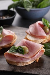 Photo of Delicious sandwiches with ham, basil and olives on table, closeup