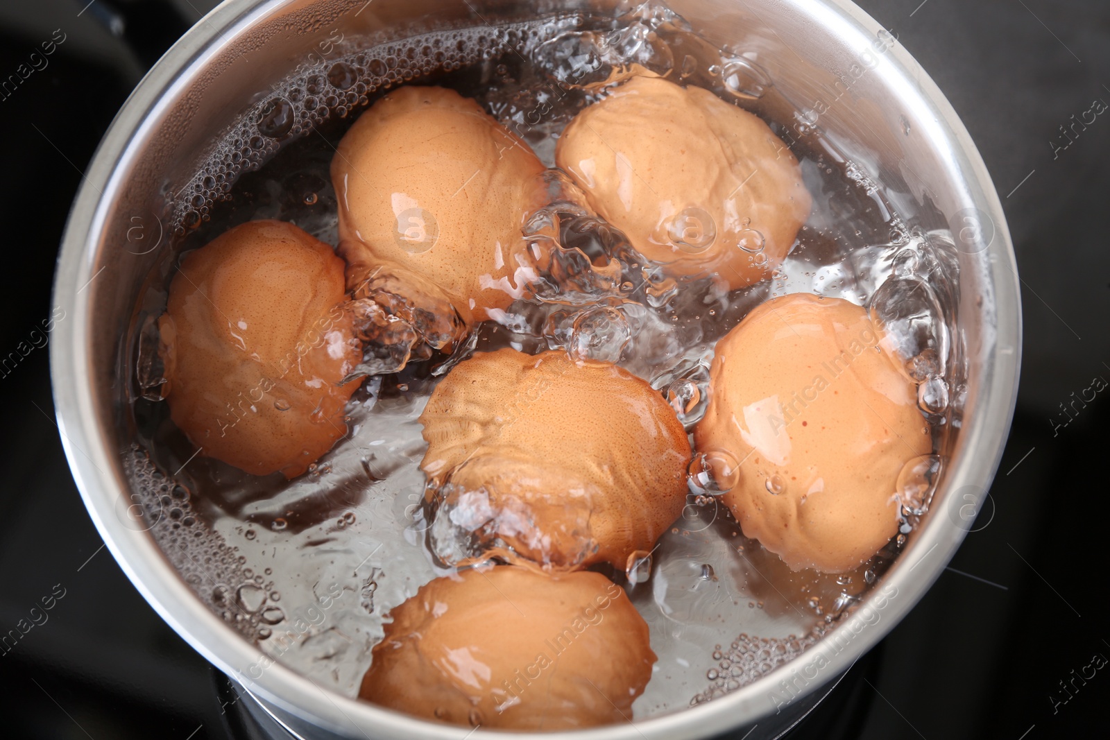 Photo of Chicken eggs boiling in saucepan on electric stove, above view