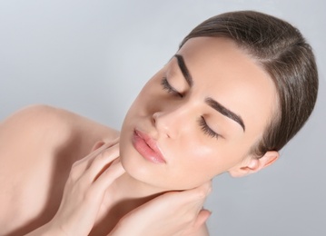 Beautiful woman with perfect eyebrows on light background