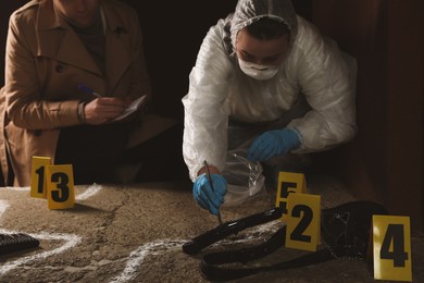 Photo of Investigator and criminologist working at crime scene outdoors in evening