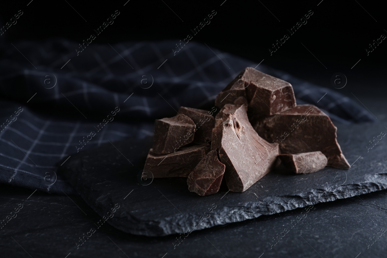 Photo of Pieces of tasty dark chocolate on black table