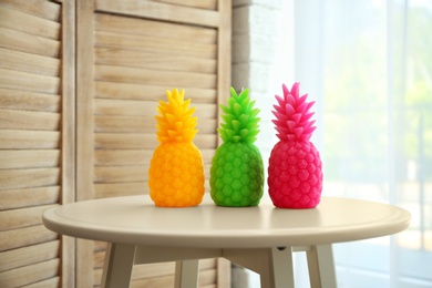 Stylish pineapple candles on table indoors. Home decorating idea