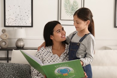 Happy mother and daughter reading book together at home. Single parenting