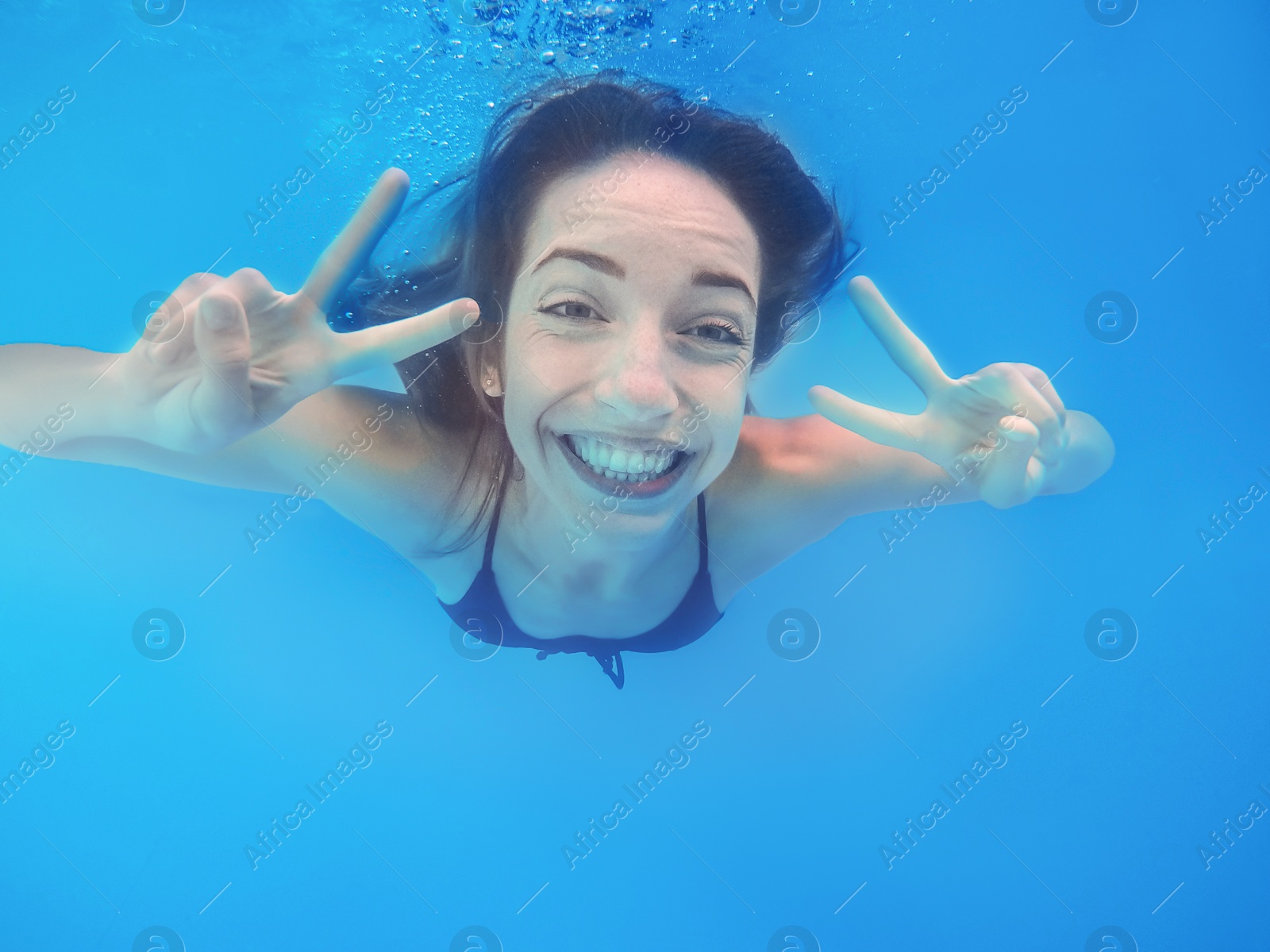 Photo of Beautiful young woman swimming in pool, underwater view